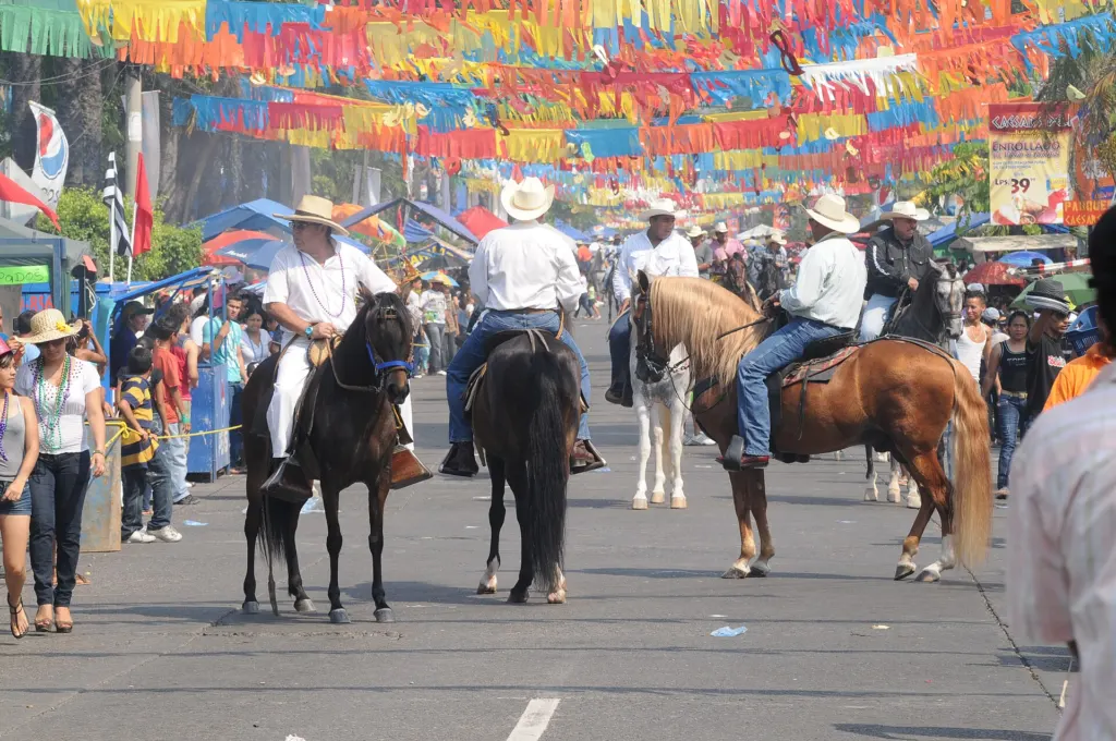 Desfile a caballo bajo banderines de colores en el Carnaval de La Ceiba